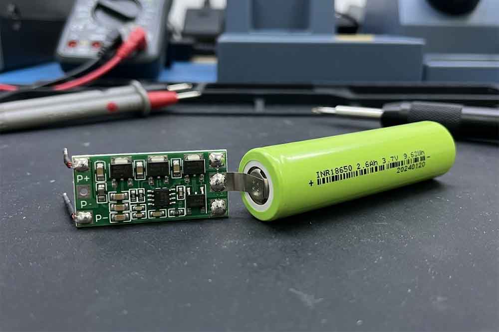 18650 battery protection PCB with electronic switching components beside a lithium-ion cell