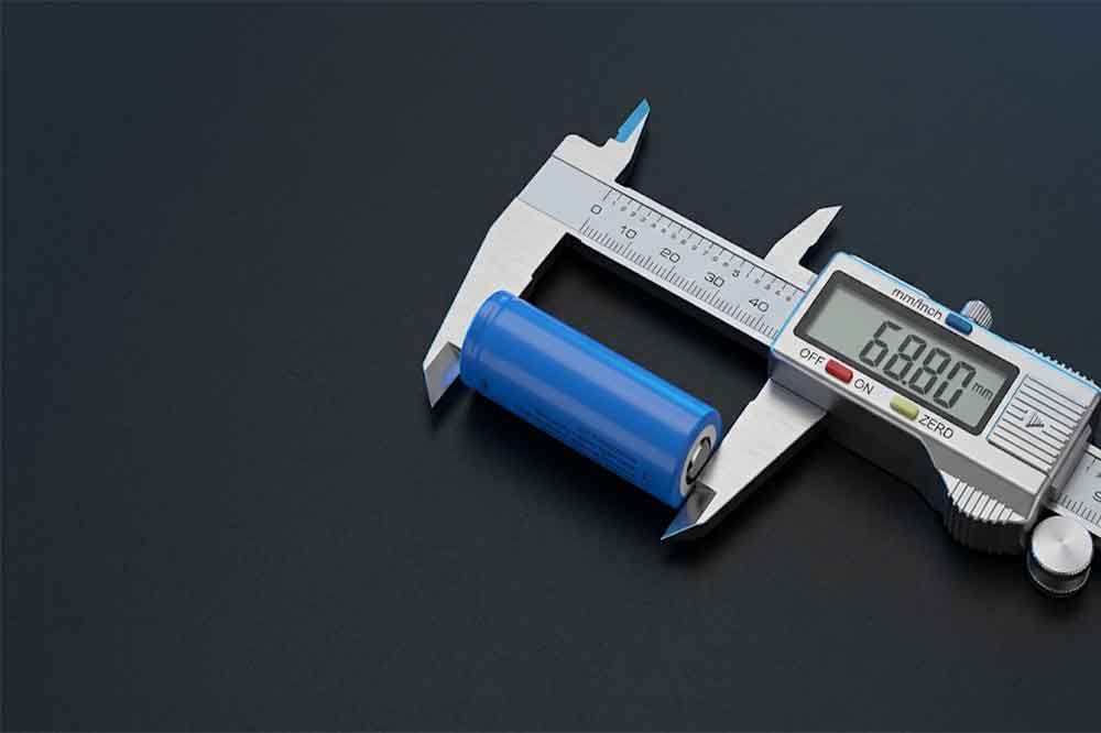 Protected 18650 lithium-ion battery beside a digital caliper for measuring battery dimensions.